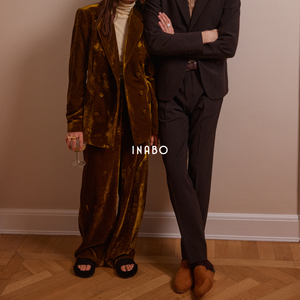 Woman wearing black open to slippers and a man wearing brown suede slippers, both from Inabo