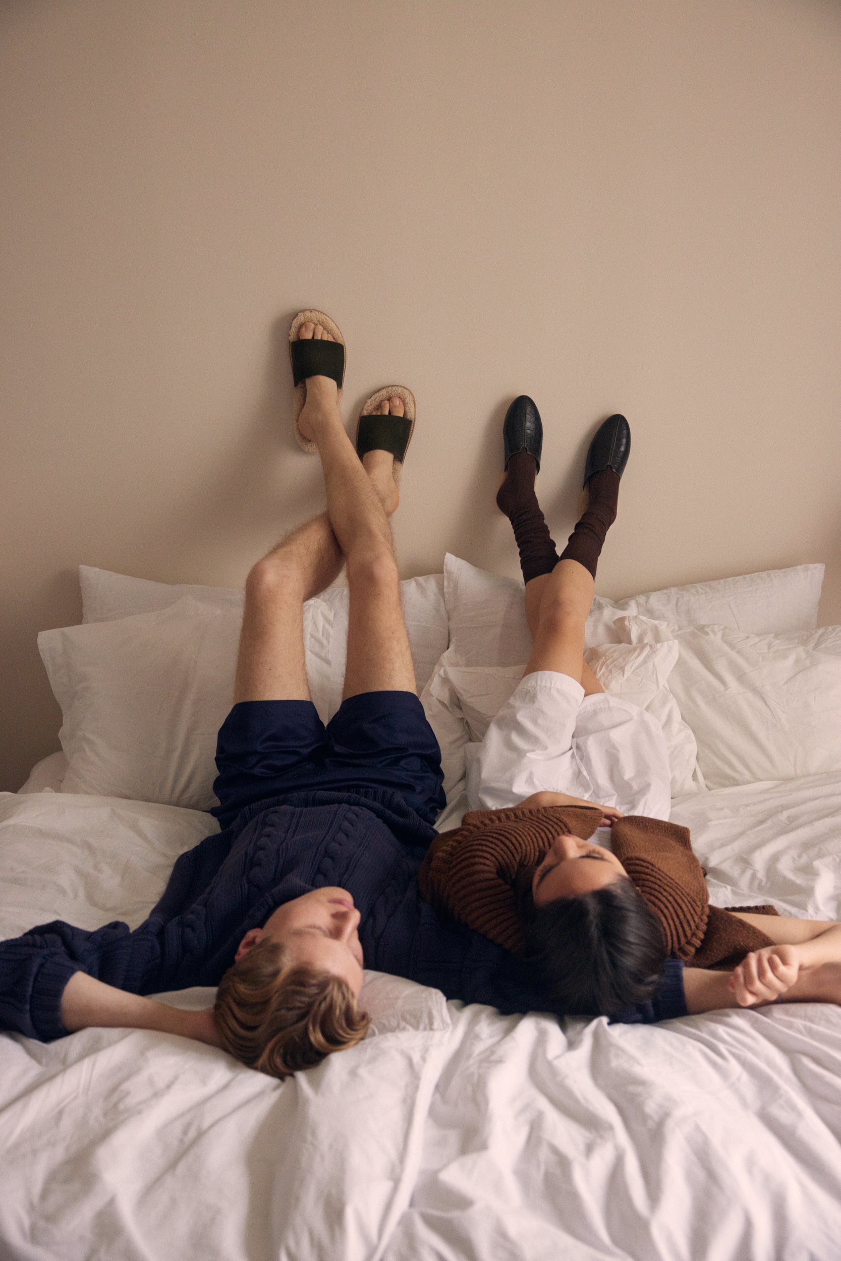 Inabo slippers worn by a man and a women lying in bed with their feet up