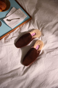 Inabo Hilma slipper in brown velvet and white shearling lying on a bed 