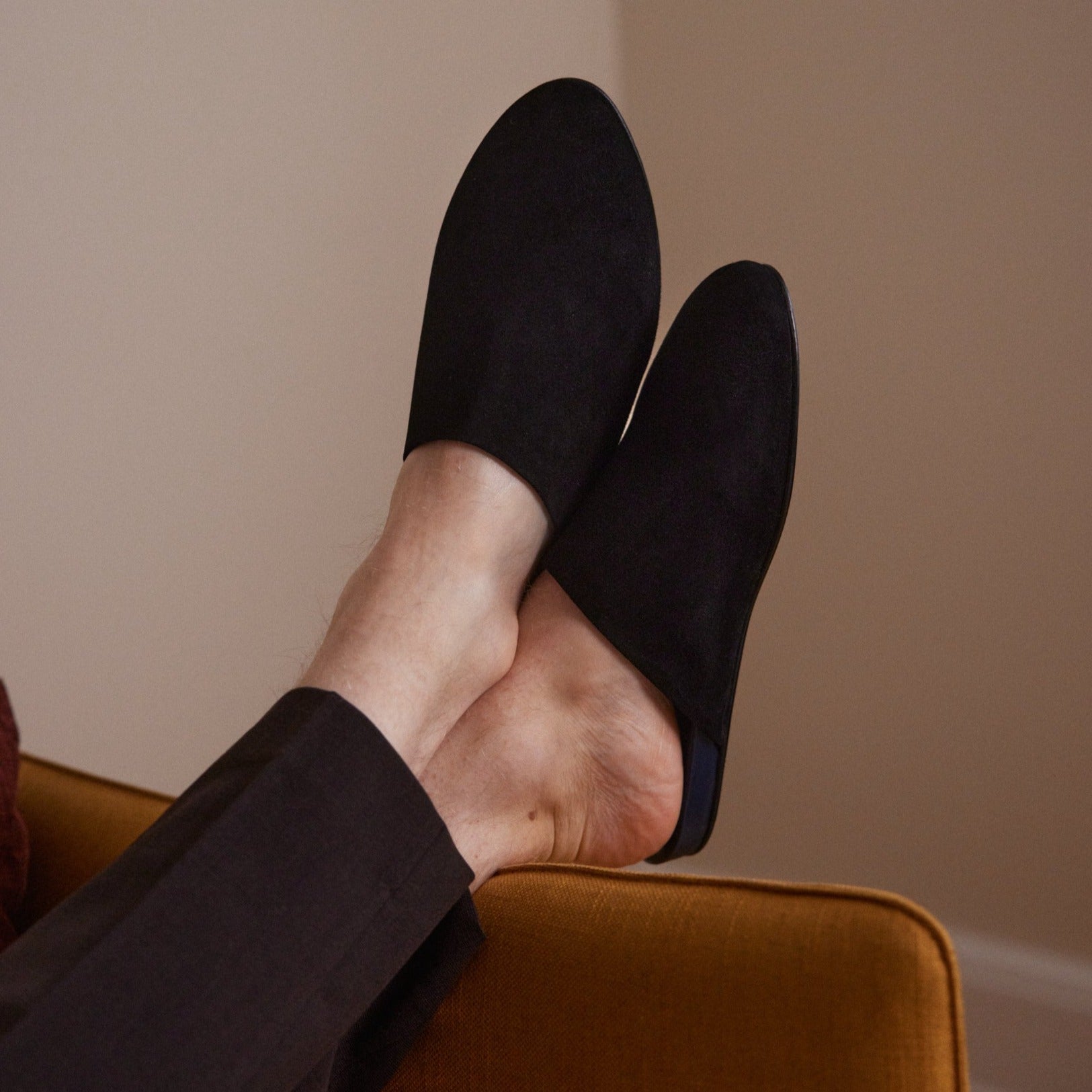 Inabo Men's Black Suede house Slipper worn by a man with his feet up on a couch